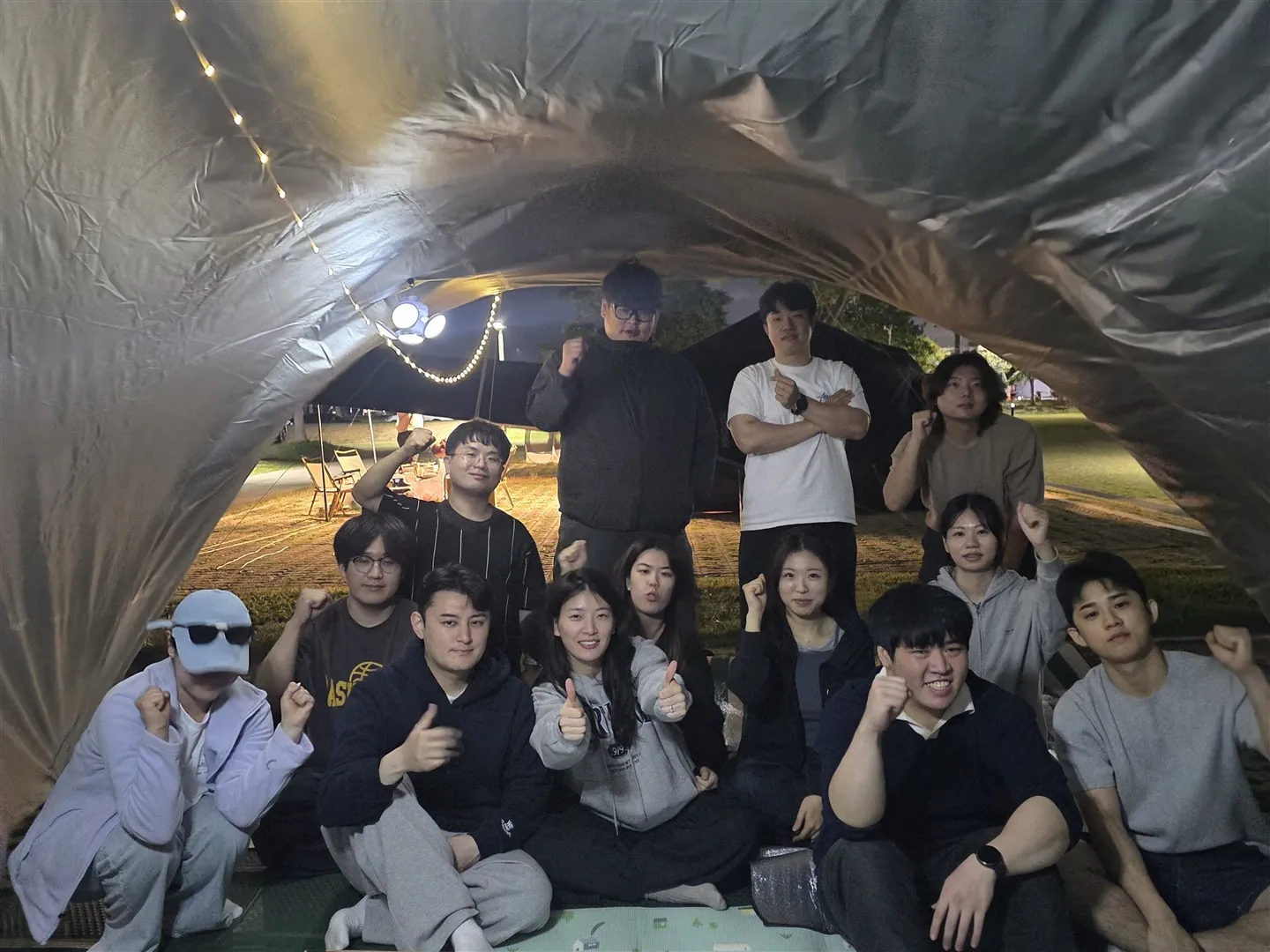밤, 전구를 단 타프 아래 모인 단체 사진